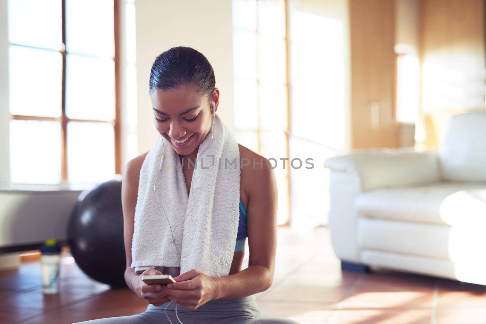 Cropped shot of a young woman checking her playlist while exercising at home.