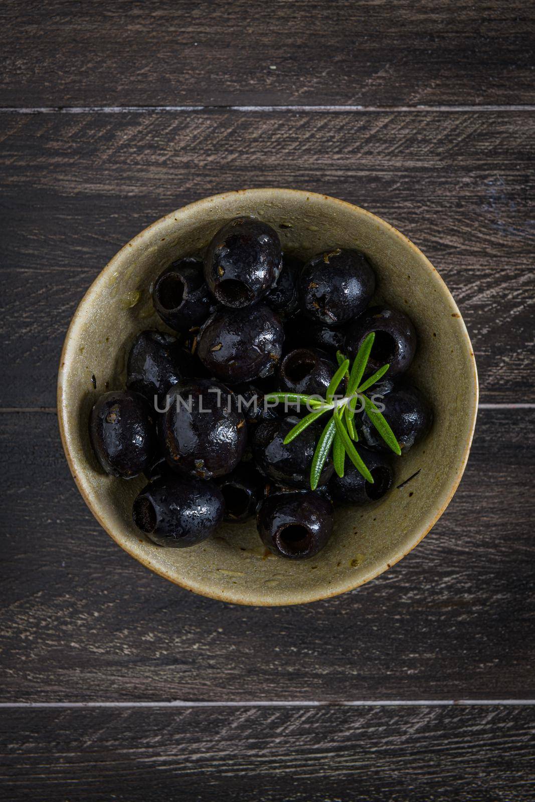 Olives in a ceramic bowl on a wooden table.