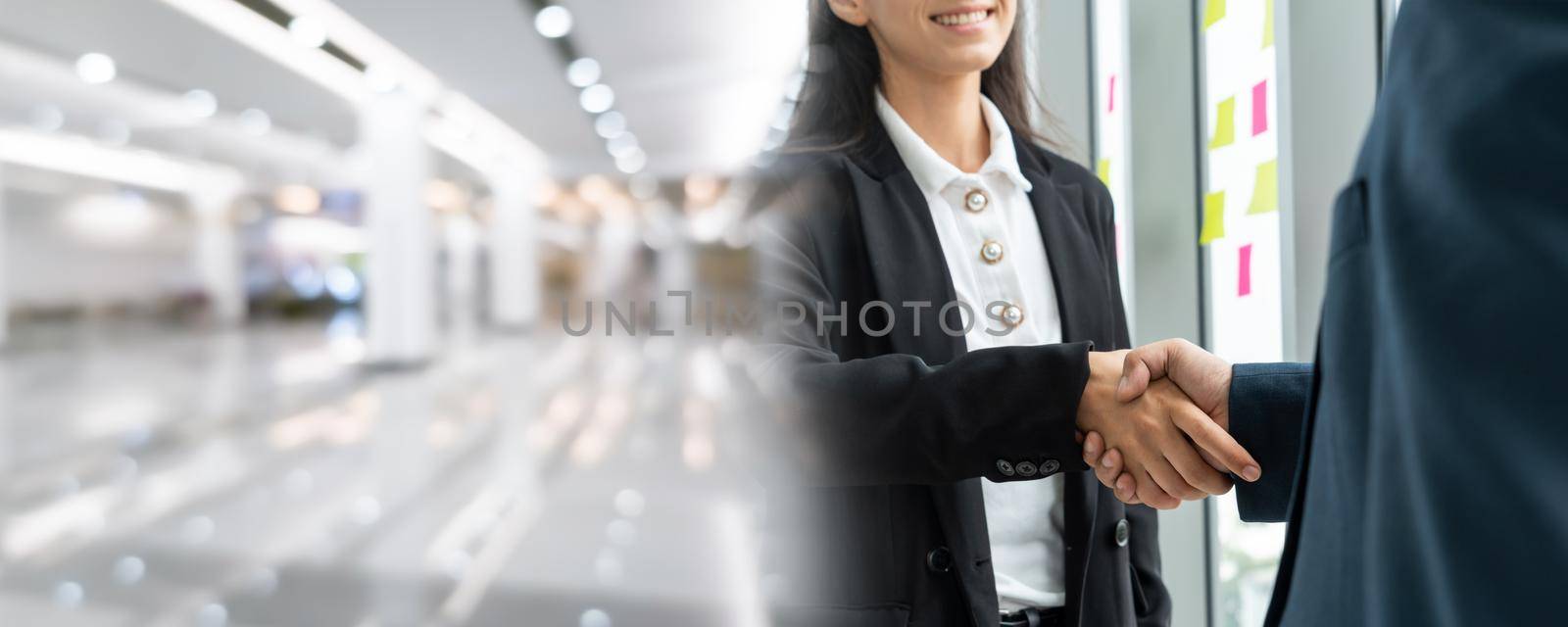 Business people handshake in corporate office in widen view showing professional agreement on a financial deal contract.