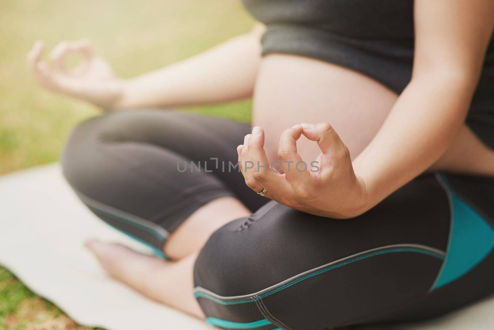 Meditating her way into motherhood. Cropped shot of an unrecognizable young pregnant woman meditating outside. by YuriArcurs