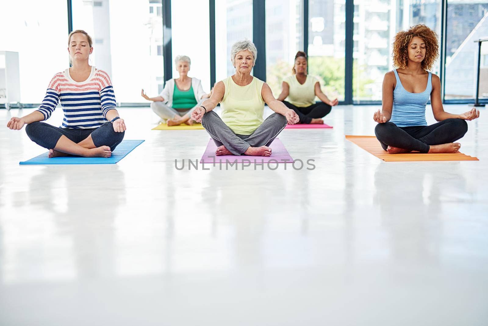 Exercise for the mind and body. Shot of a group of women meditating indoors. by YuriArcurs