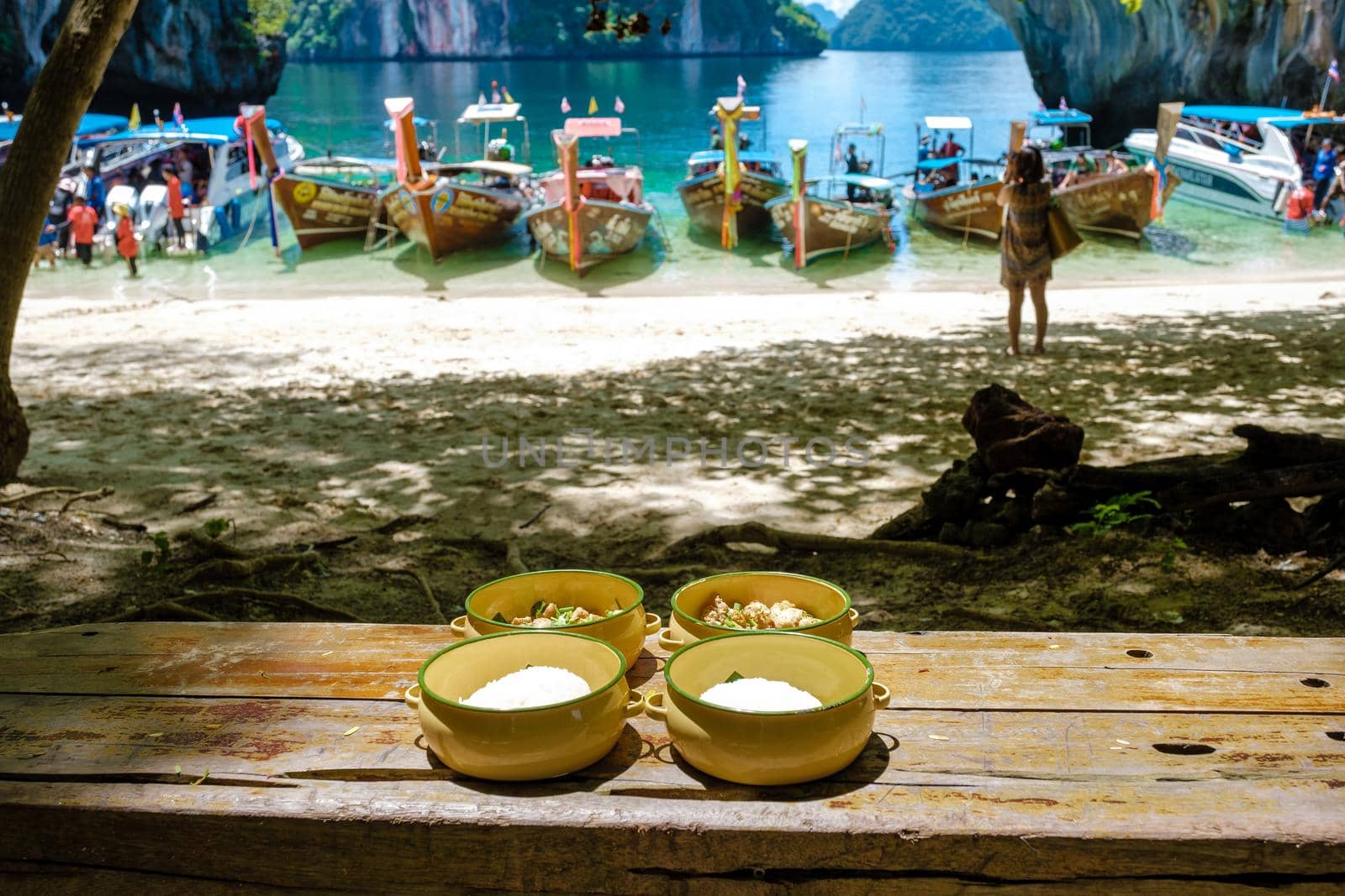 Koh Lao Lading near Koh Hong Krabi Thailand, beautiful beach with longtail boats, a couple of European men, and an Asian woman on the beach.