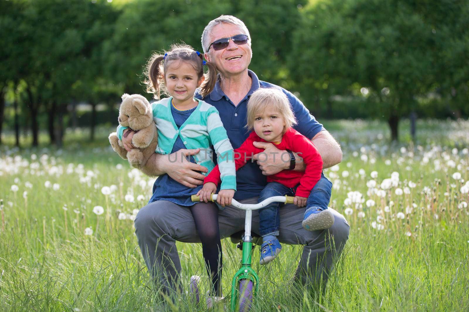 Happy Older grandfather with two kids lying on grass In park