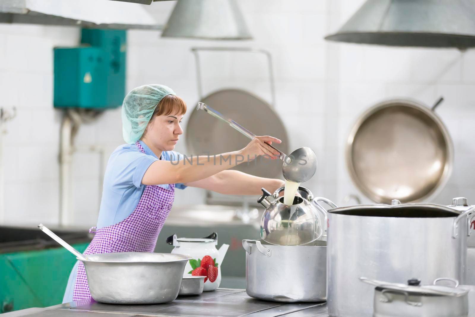 Cook prepares food. Cook with large pans and a ladle. Kitchen worker with a ladle. Chef professional