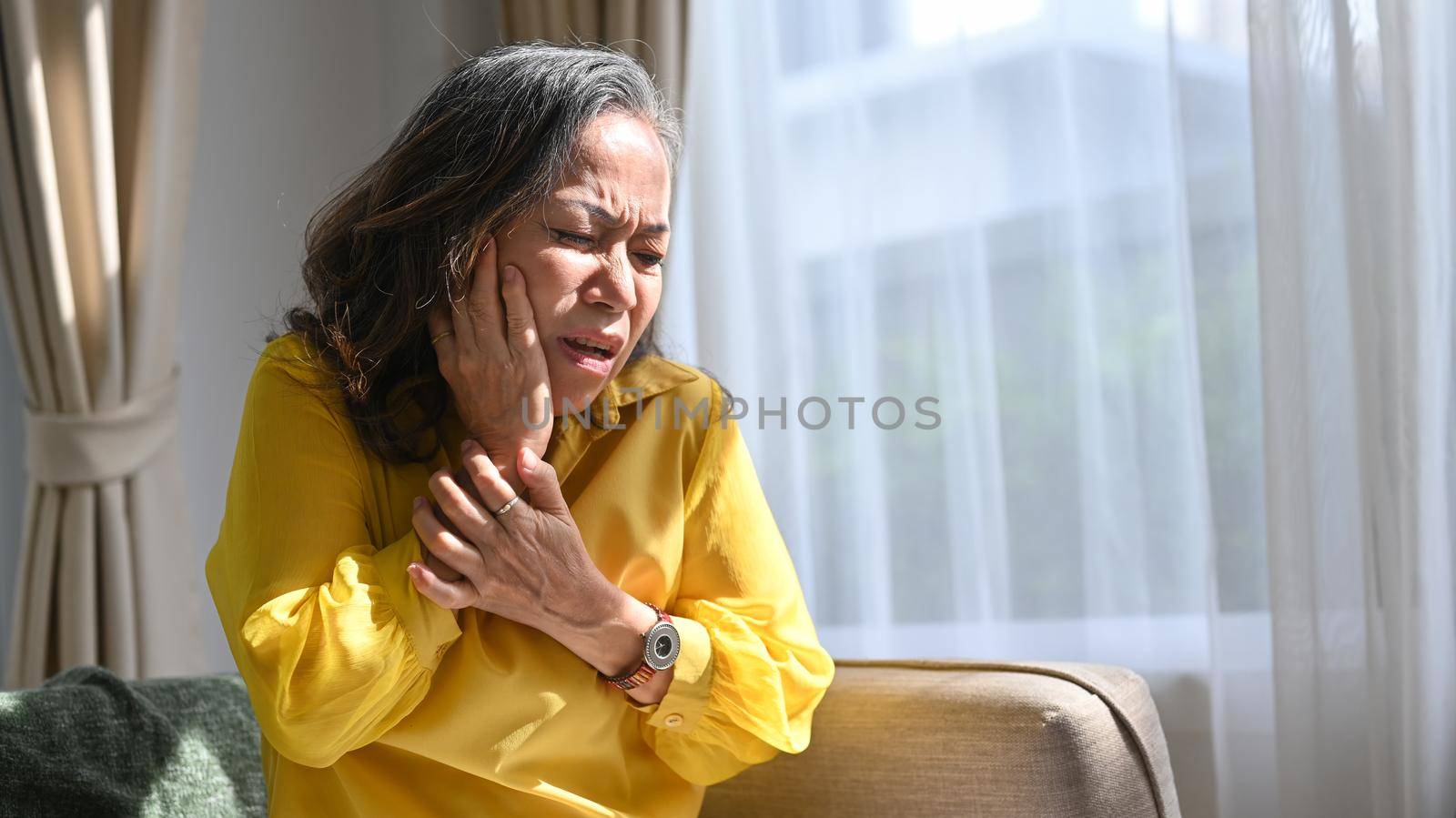Mature woman touching sore cheek suffering from toothache cavities, need dental service help, medical insurance concept by prathanchorruangsak