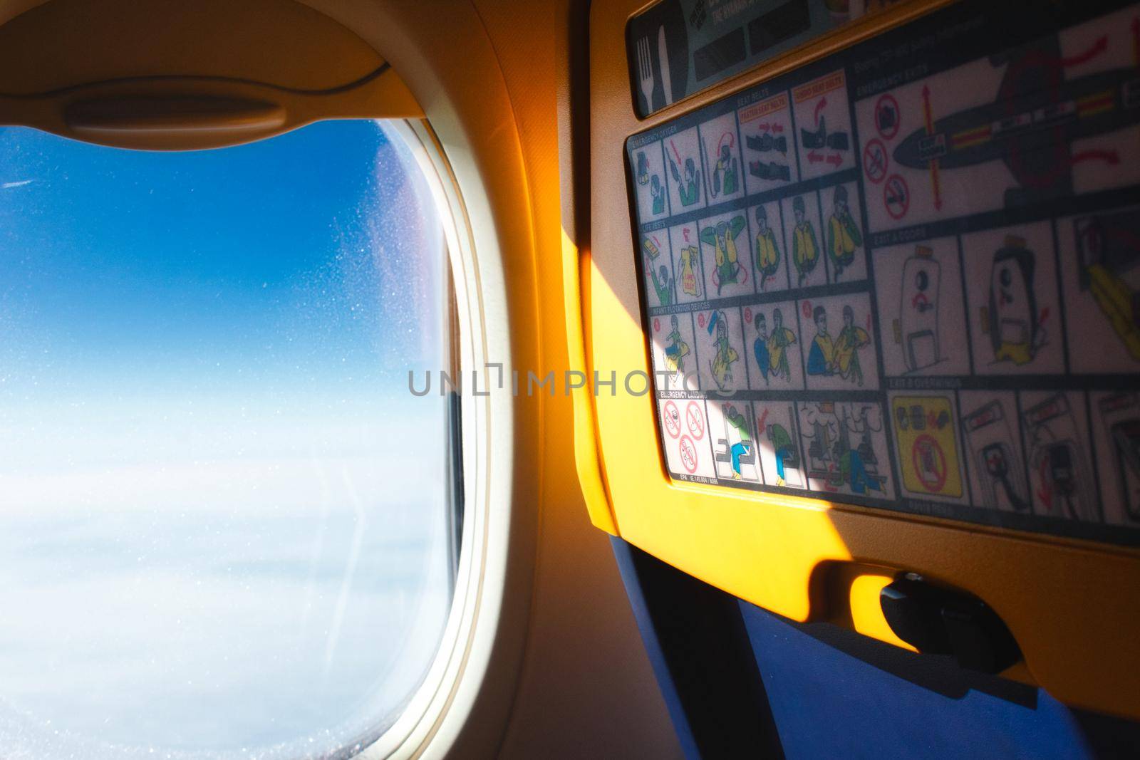 View of open window and back of passenger seat on a plane in the air