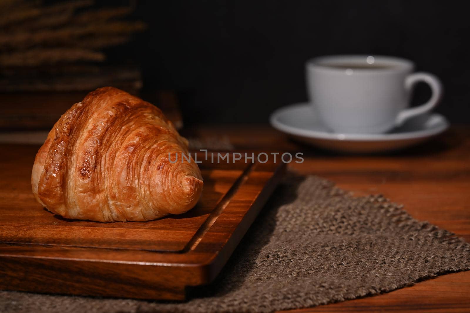 Fresh homemade butter croissant and coffee cup on wooden table. Breakfast, bread bakery products cafe concept.