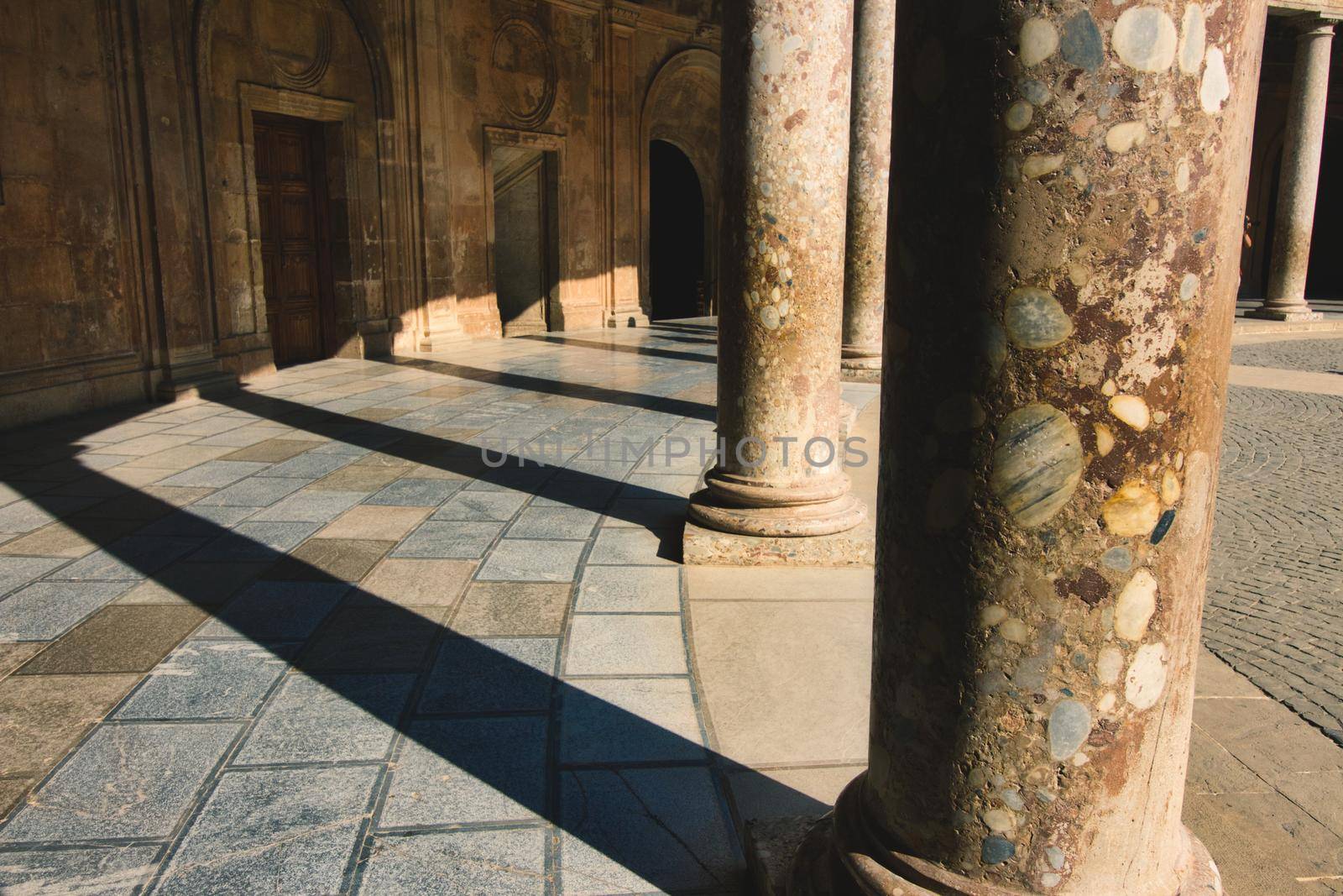 Columns casting shadows in the Charles V Palace at the Alhambra in Granada, Spain by tennesseewitney
