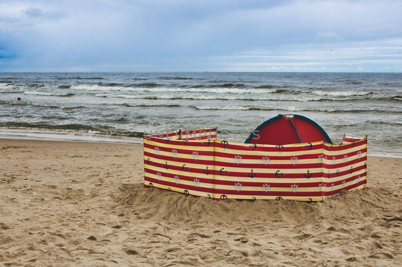 A wind-breaker and tent on the sand at the beach