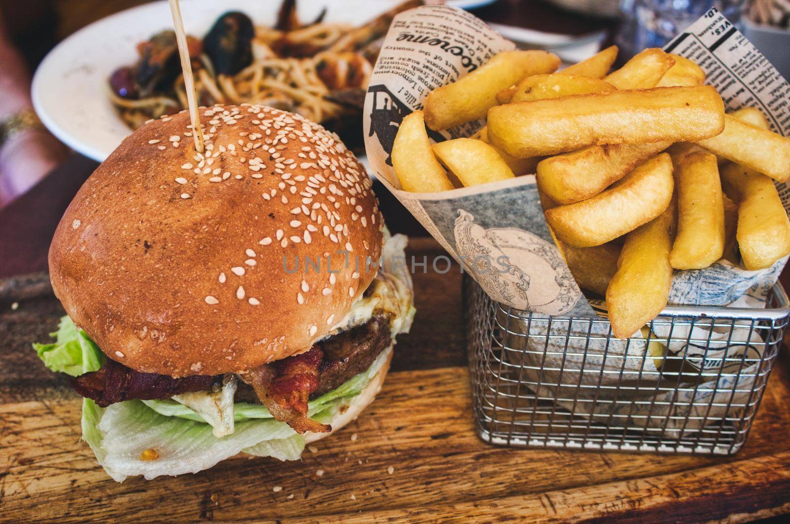 Burger and fries / chips in a basket on a wooden board in a restaurant