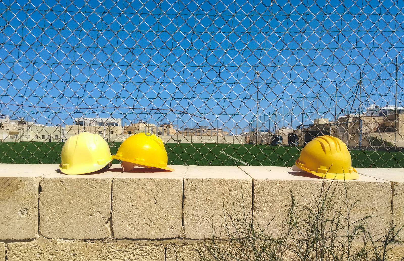 Yellow hard hats on a wall at a construction site by tennesseewitney