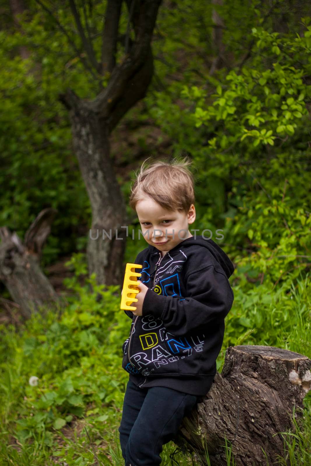 Portrait of a child with a funny facial expression. a walk in the fresh air in the park. Bright and juicy spring greenery around.