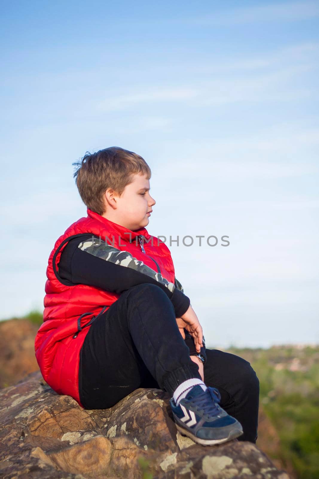 A child sits on top of a cliff and watches what is happening below. panoramic view from the top of a rocky mountain. Russia, Rostov region, skelevataya skala, the 7th wonder of the Don world. Landscape