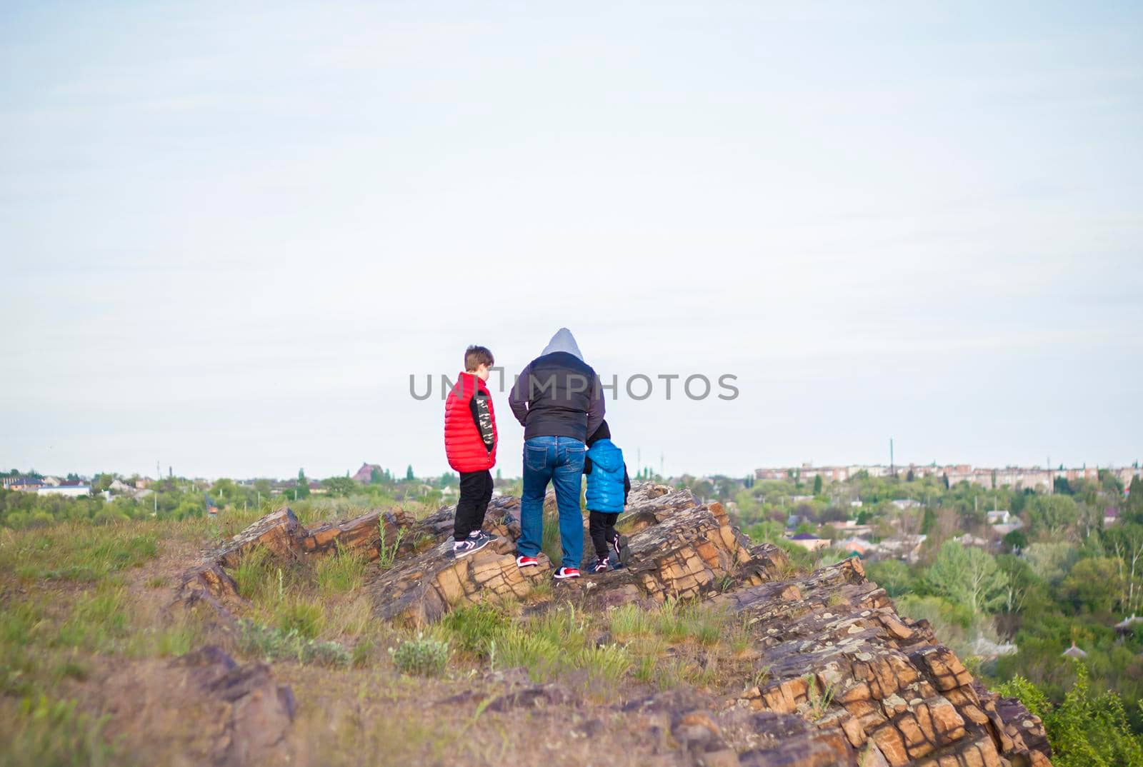 A man and children are standing on a rock and watching what is happening below. panoramic view from above. Russia, Rostov region, skelevataya skala, the 7th wonder of the Don world. by Alina_Lebed