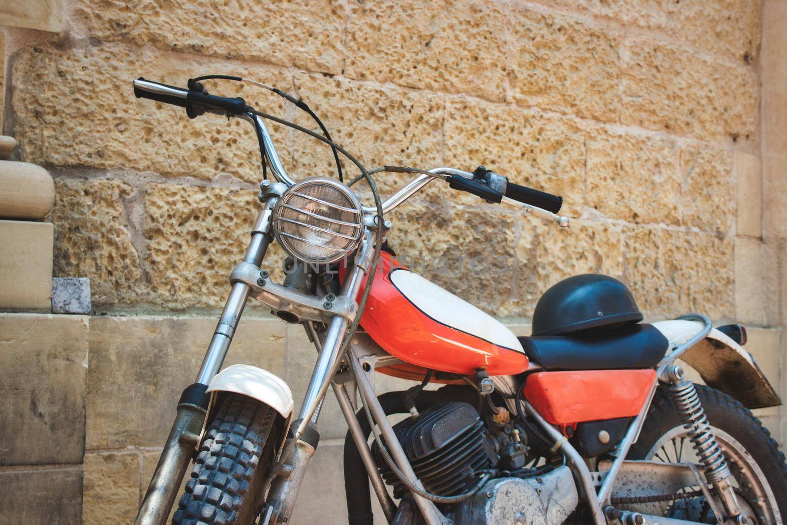 Old vintage motorbike against a rural village wall