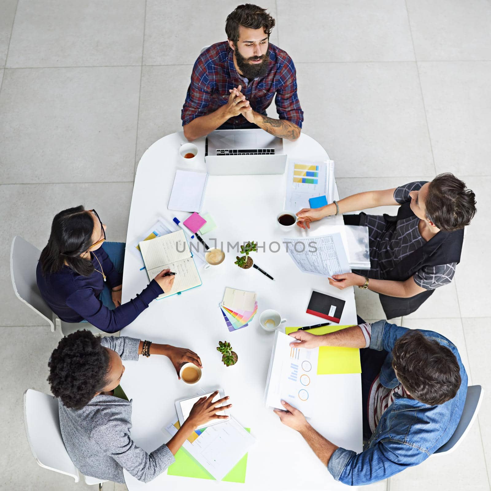 How are plans coming along with the latest project. High angle shot of coworkers having a meeting in a modern office. by YuriArcurs