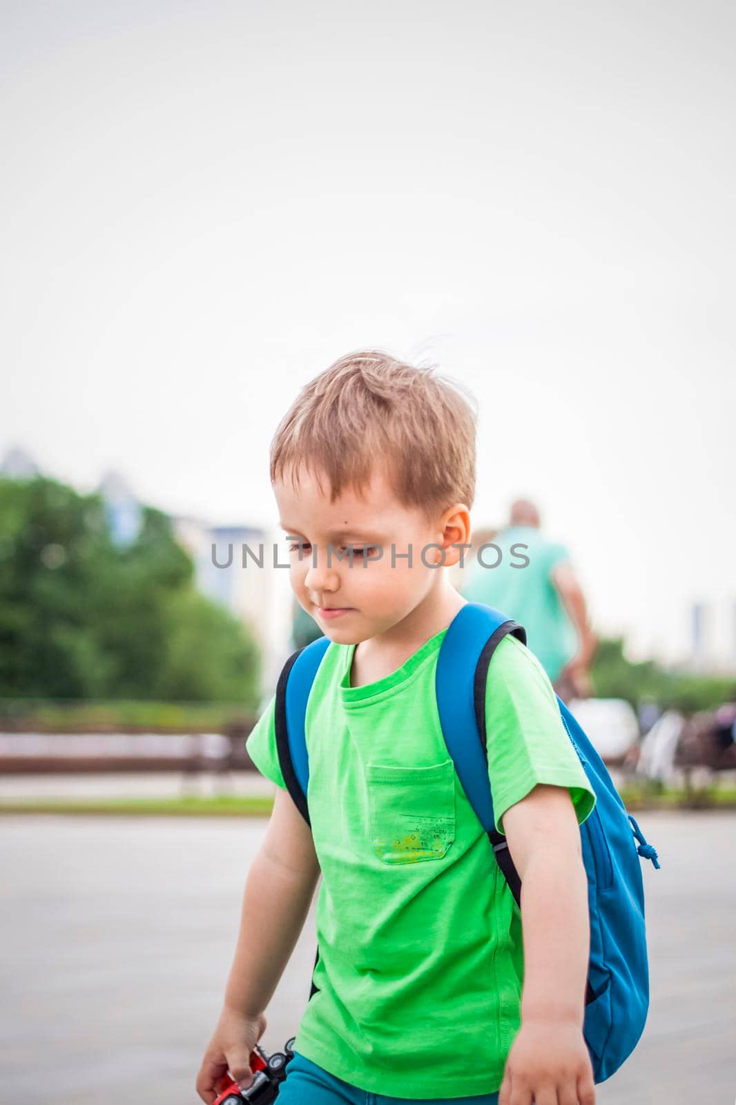 Portrait of a child, a boy against the backdrop of urban landscapes of skyscrapers and high-rise buildings in the open air. Children, Travel. Lifestyle in the city. Center, streets. Summer, a walk.