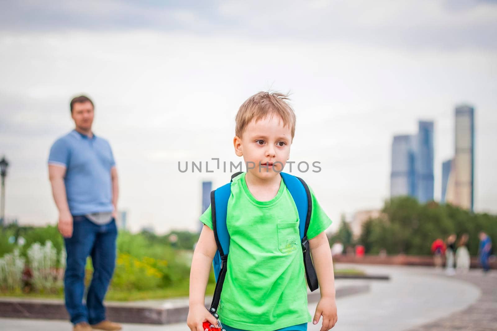 Portrait of a child, a boy against the backdrop of urban landscapes of skyscrapers and high-rise buildings in the open air. Children, Travel. Lifestyle in the city. Center, streets. Summer, a walk.
