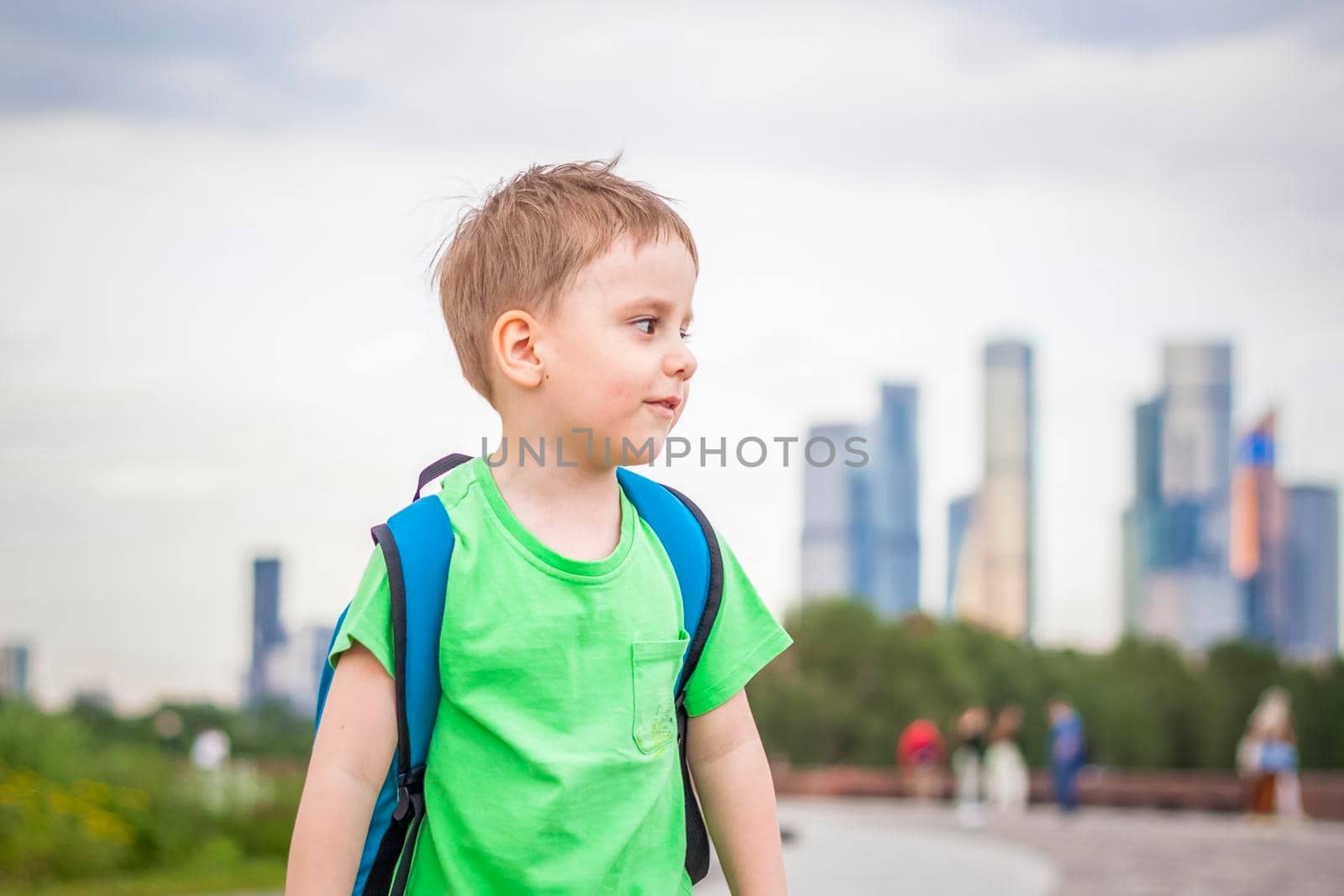 Portrait of a child, a boy against the backdrop of urban landscapes of skyscrapers and high-rise buildings in the open air. Children, Travel. Lifestyle in the city. Center, streets. Summer, a walk.