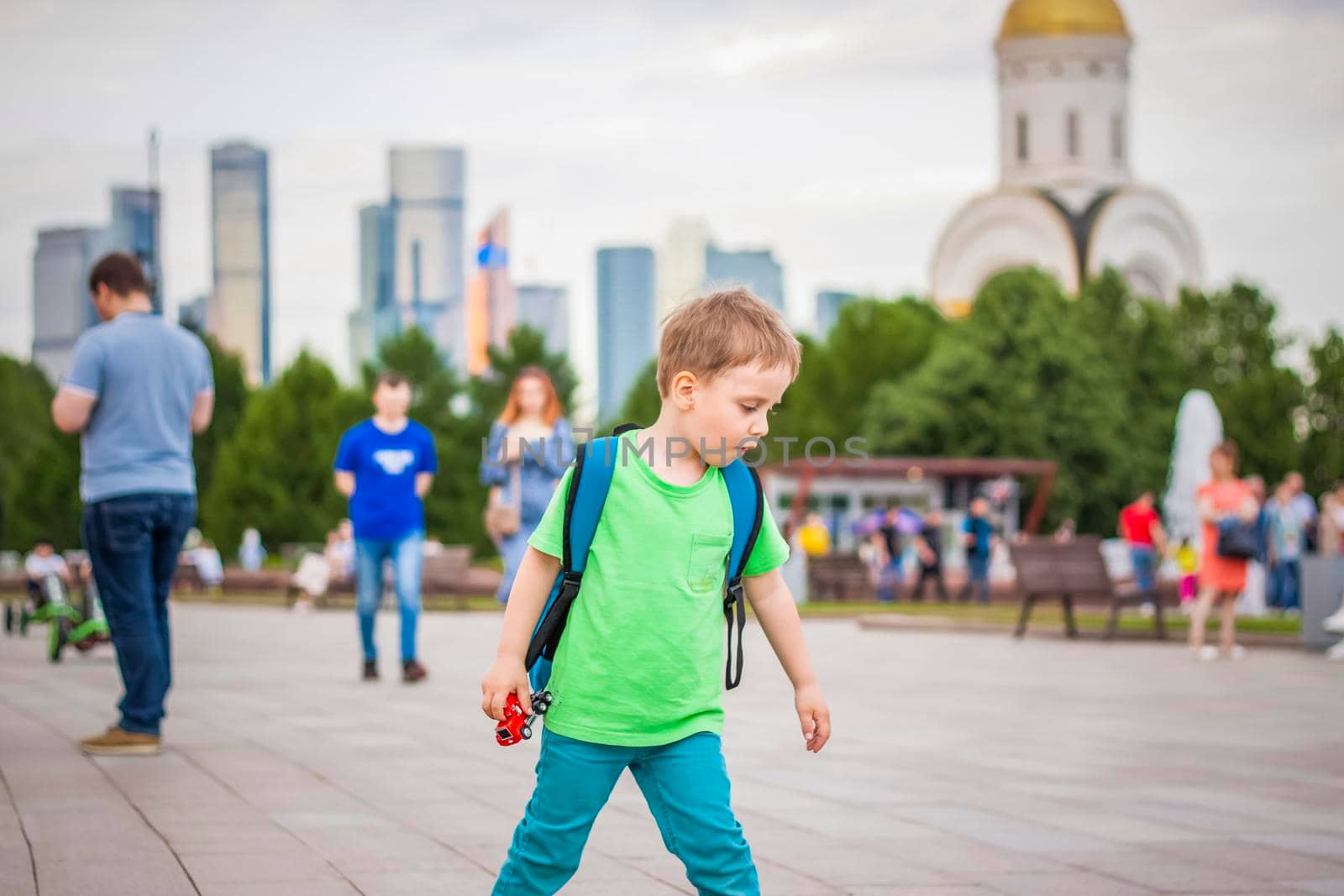 Portrait of a child, a boy against the backdrop of urban landscapes of skyscrapers and high-rise buildings in the open air. Children, Travel. Lifestyle in the city. Center, streets. Summer, a walk.