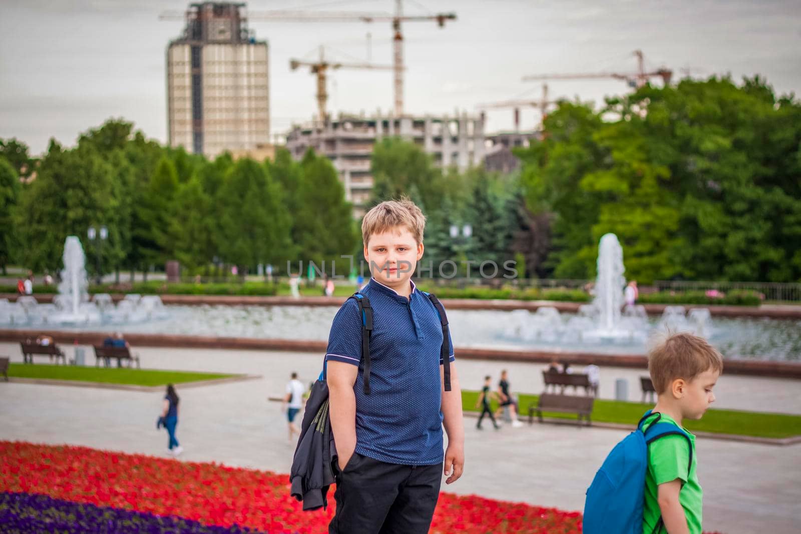 Portrait of a child, a boy against the backdrop of urban landscapes of skyscrapers and high-rise buildings in the open air. Children, Travel. Lifestyle in the city. Center, streets. Summer, a walk.