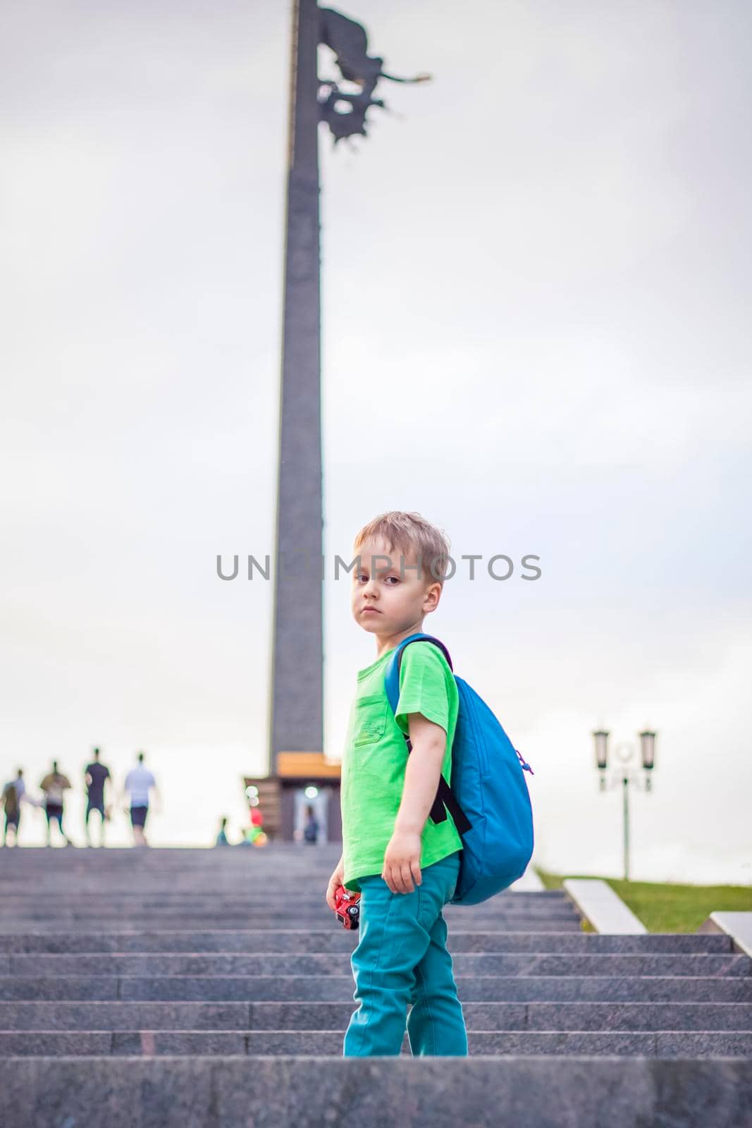 Portrait of a child, a boy against the backdrop of urban landscapes of skyscrapers and high-rise buildings in the open air. Children, Travel. Lifestyle in the city. Center, streets. Summer, a walk.