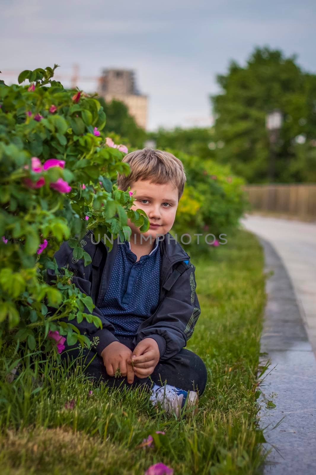 Portrait of a child, a boy against the background of plants in an open-air park. Children, Travel. Lifestyle in the city. Center, streets. Summer, a walk.