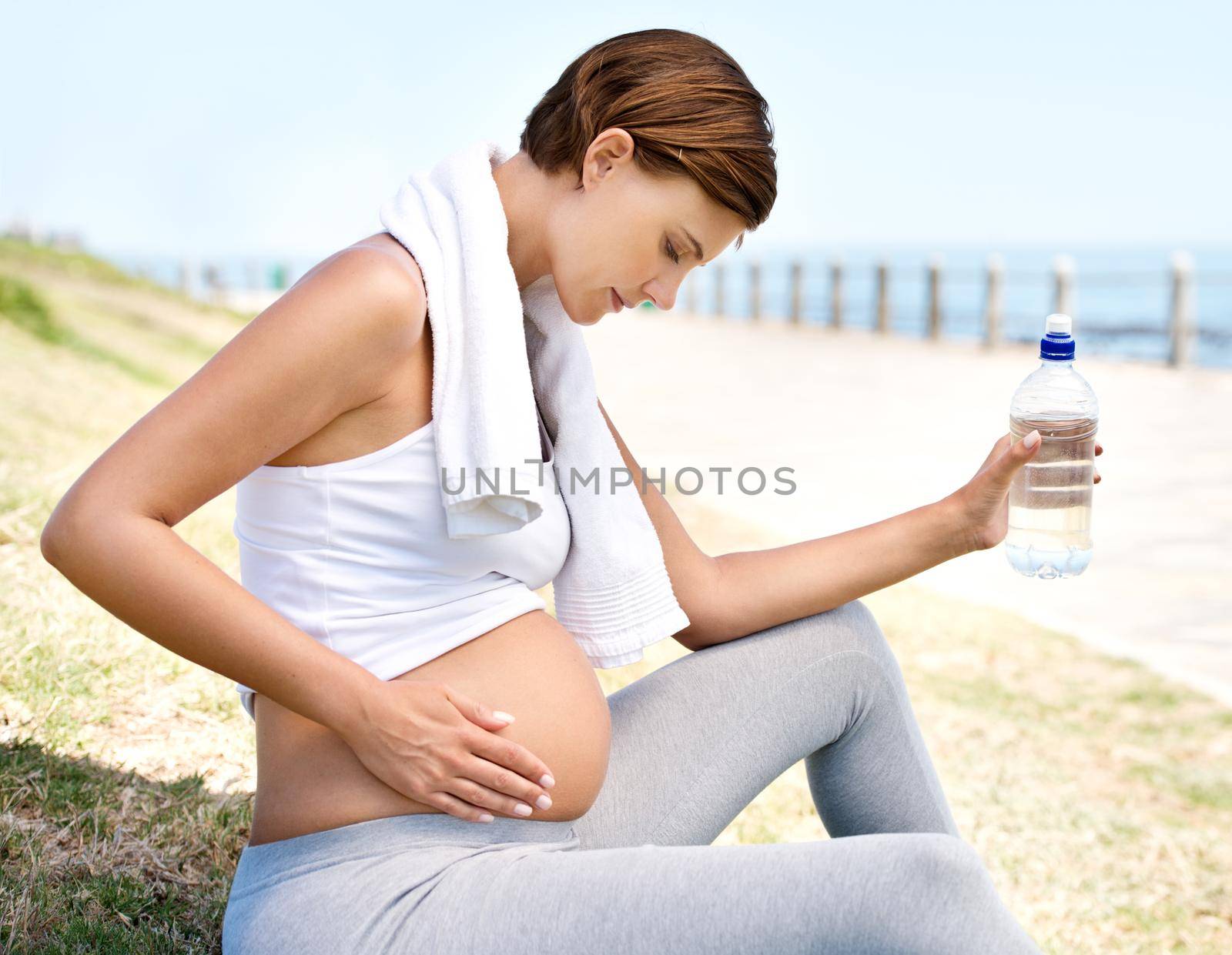 Healthy mom = healthy baby. A pregnant woman resting from her workout outdoors. by YuriArcurs