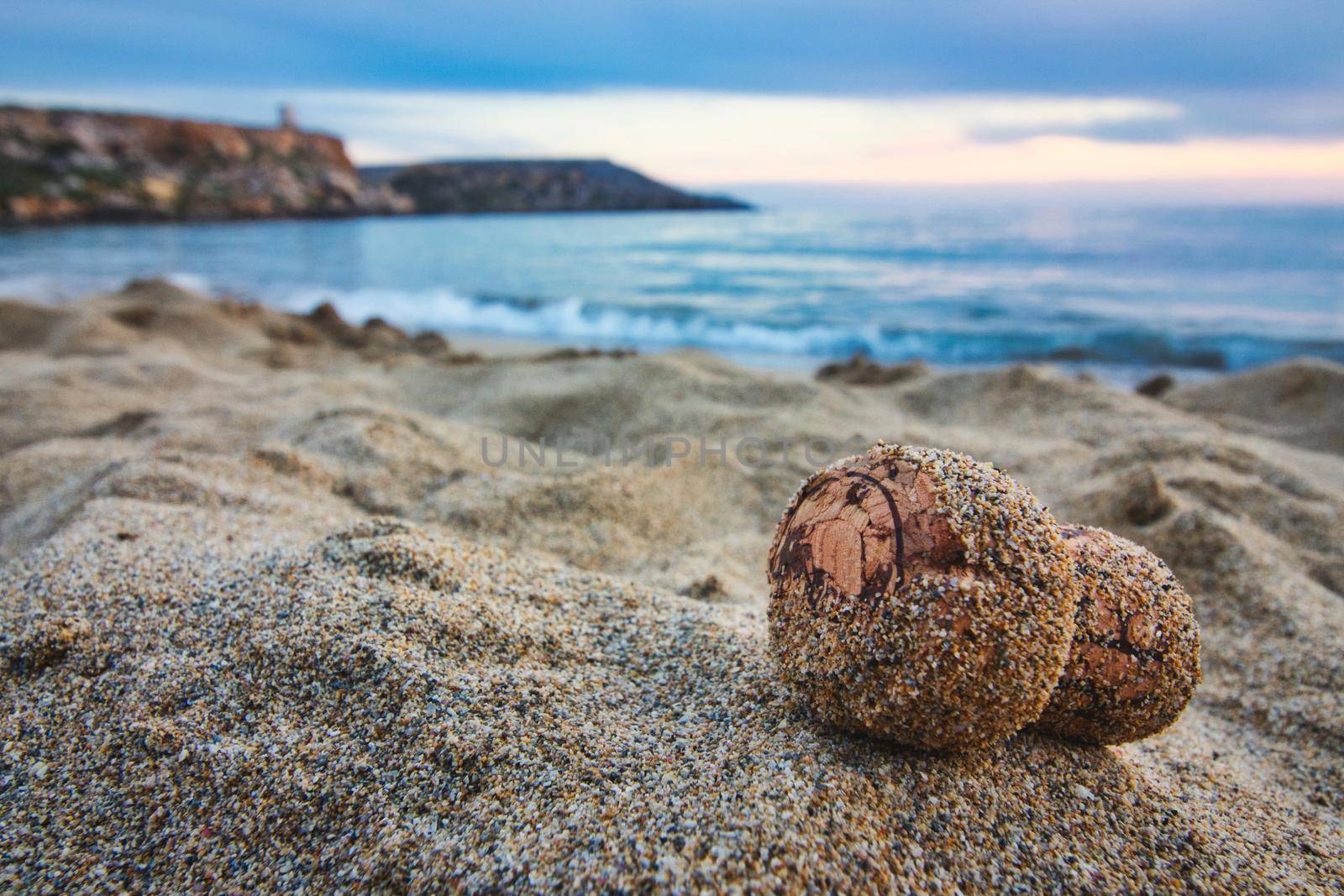 Close-up of champagne cork on a sandy beach with the sea in the background by tennesseewitney