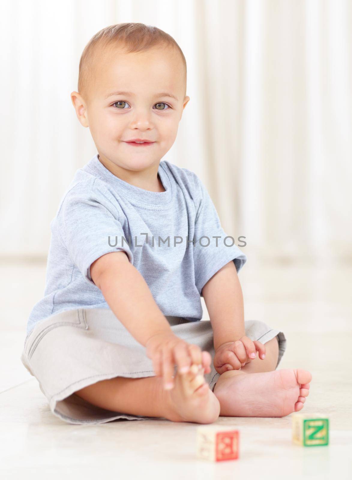 Full length shot of a cute little boy playing at home with some wooden blocks.