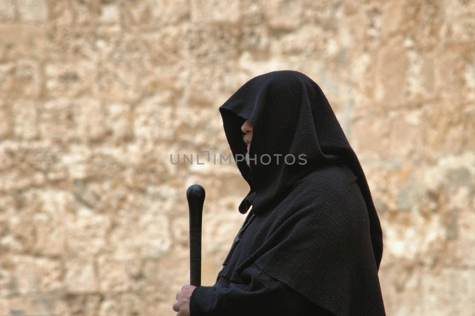 Hooded spooky looking medieval monk in a traditional black robe with staff