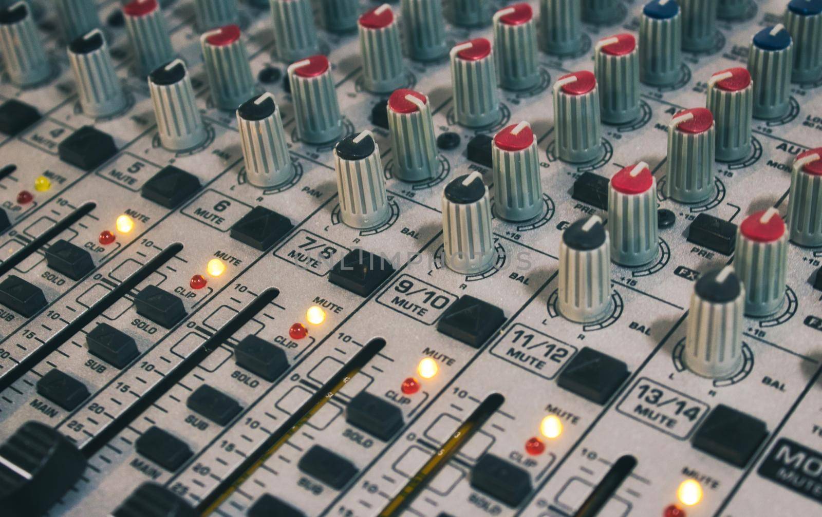 Close-up of audio mixing desk with knobs and sliders
