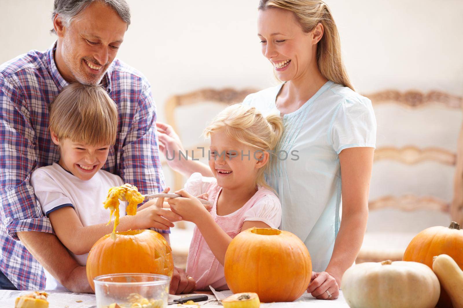 Pumpkin carving. A family of four carving pumpkins for halloween. by YuriArcurs