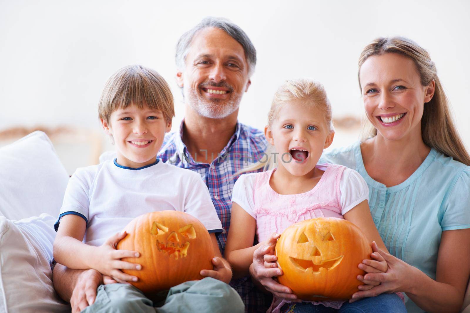 Portrait of a family of four showing you their carved pumpkins.