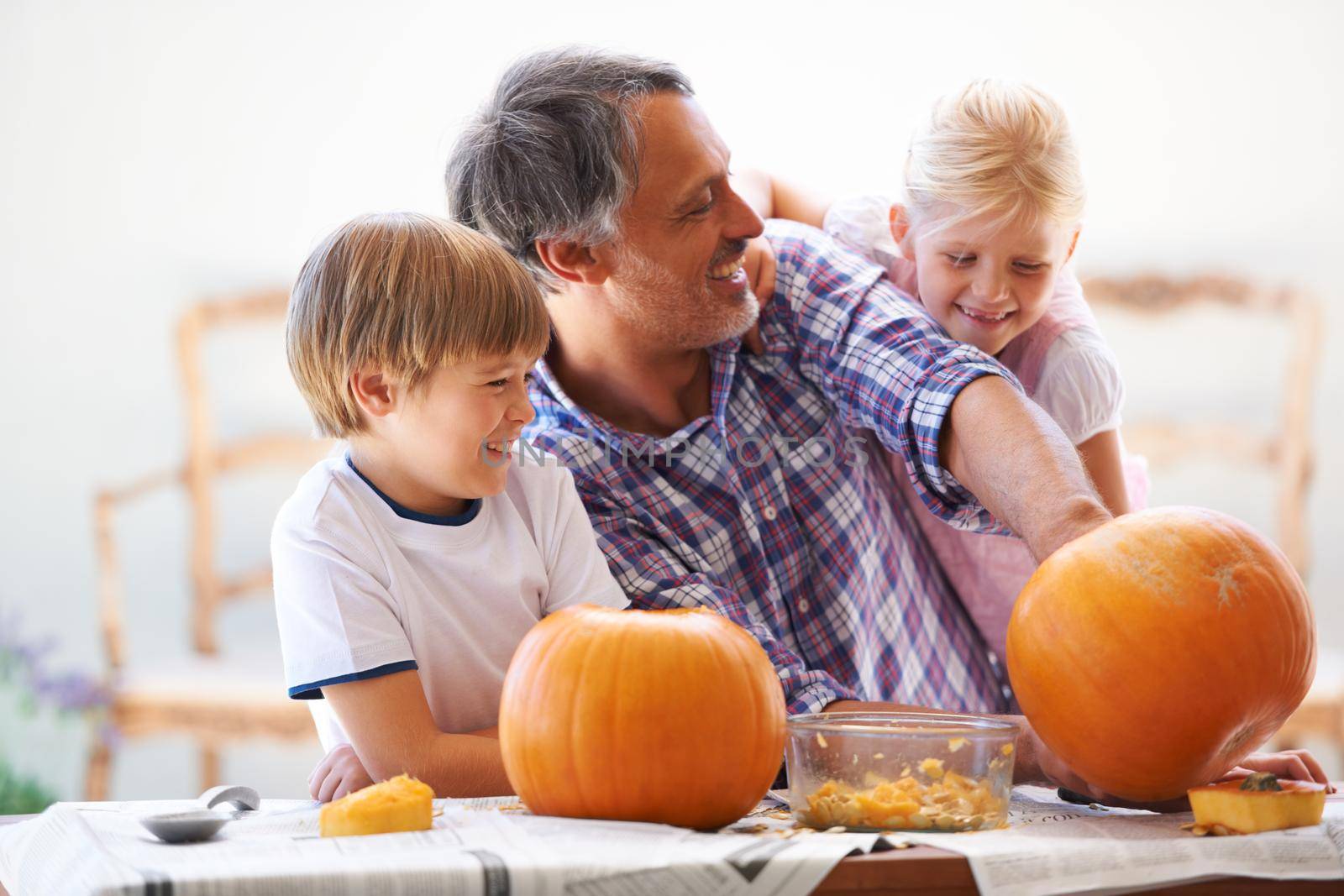 A father, his son and his daughter hollowing out pumpkins for halloween.