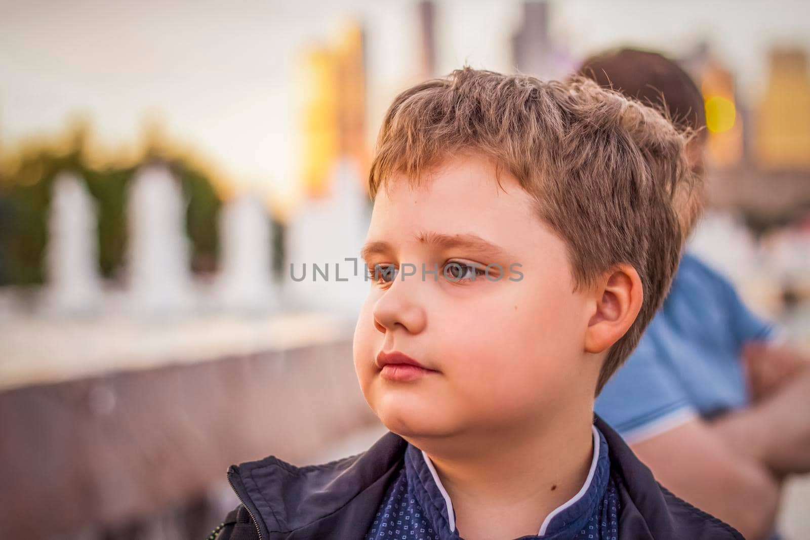 Portrait of a child, a boy against the backdrop of urban landscapes of skyscrapers and high-rise buildings in the open air. Children, Travel. Lifestyle in the city. Center, streets. Summer, a walk.