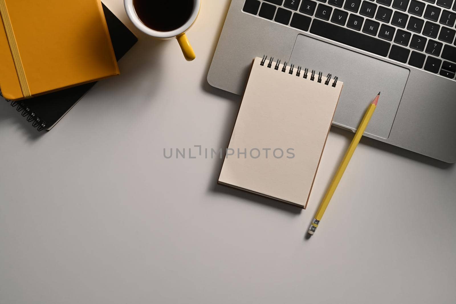 Top view white office desk with notepad, pencil, laptop computer and coffee cup. by prathanchorruangsak