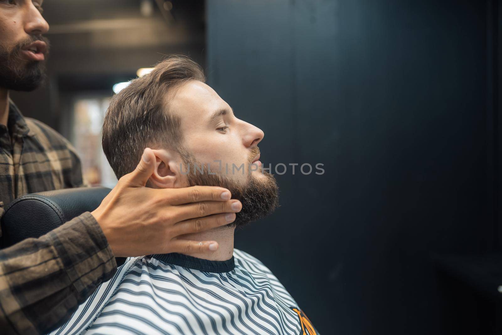 Facial applying lotion after shave in Barber shop. Master hands close up