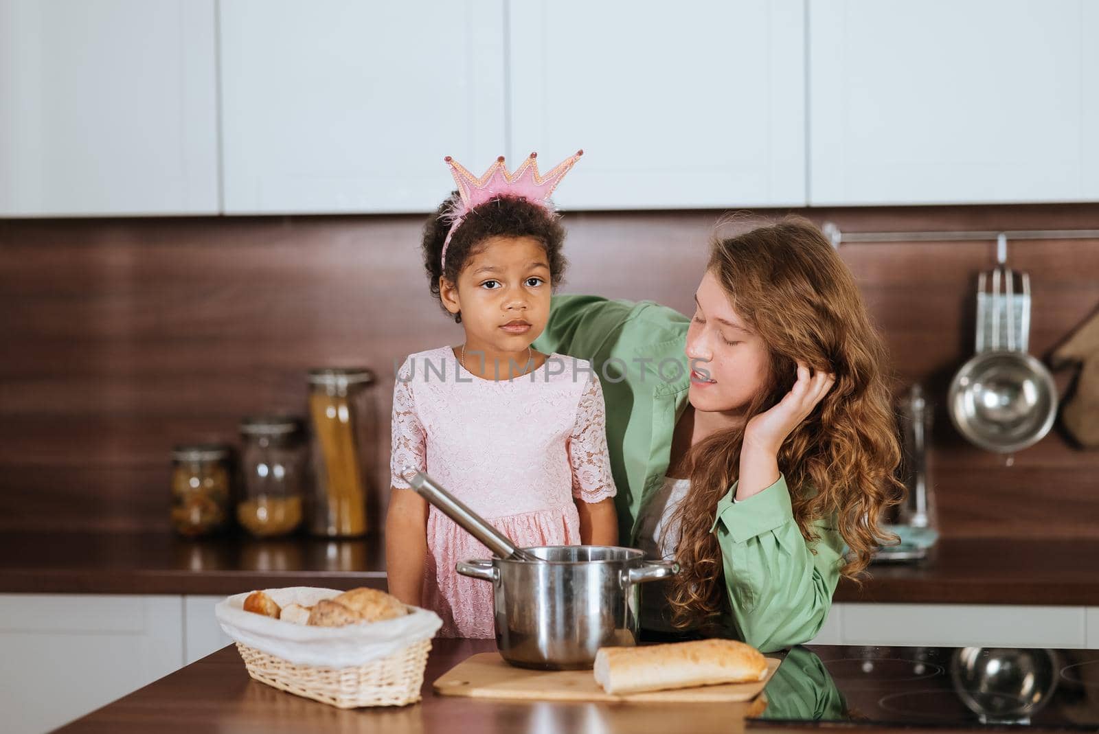 Happy mommy and daughter girl having fun while cooking in kitchen. Ethnically and racially mixed family