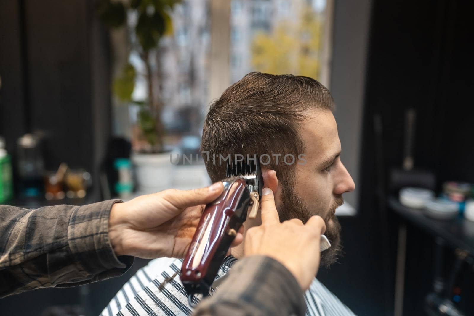 Men's hairstyling and haircutting with hair clipper in a barber shop or hair salon