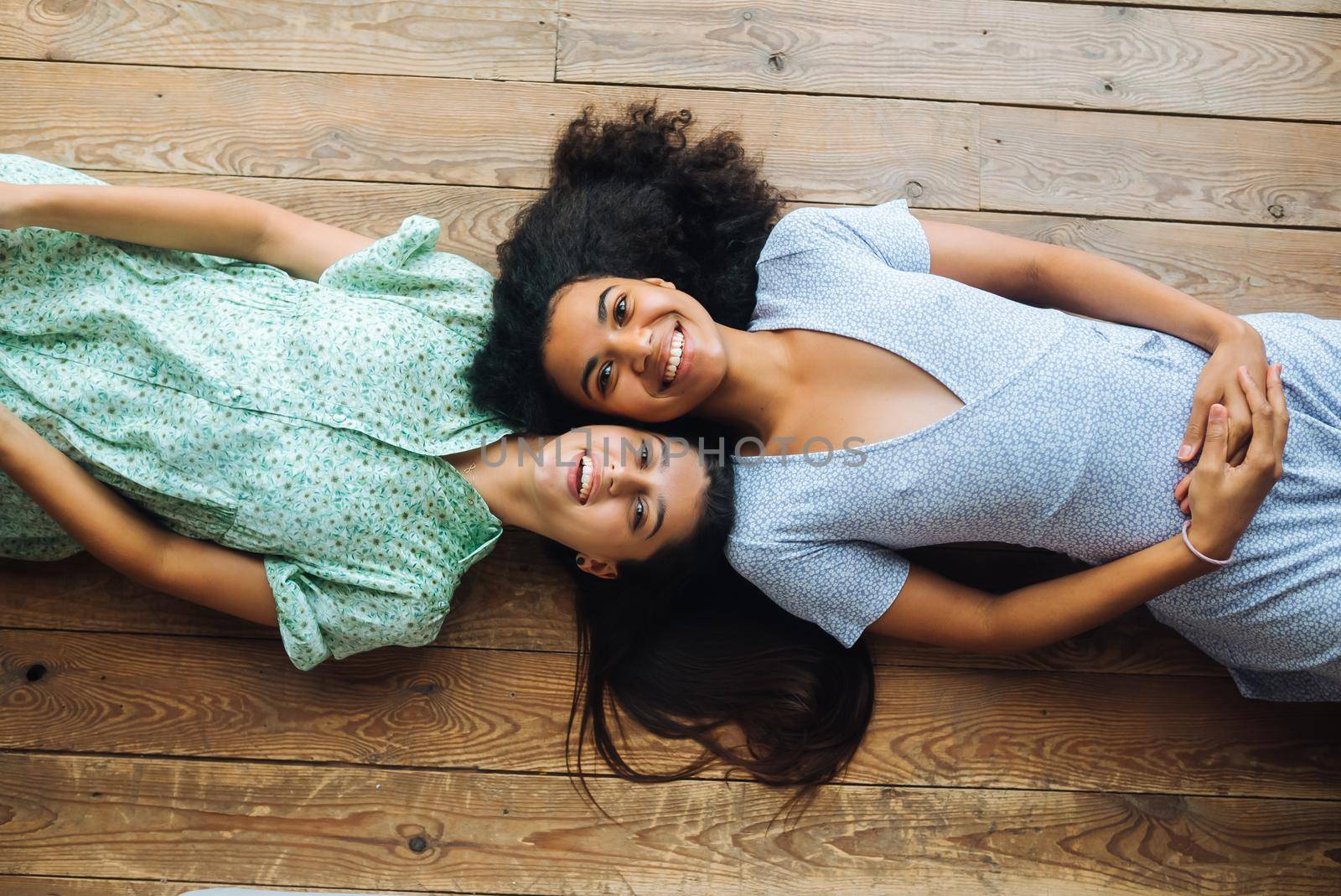 Two young women lie head to head on the floor, top view