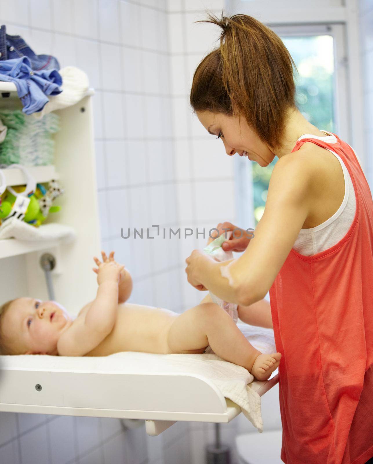 Cute young mom changing a babys diaper.