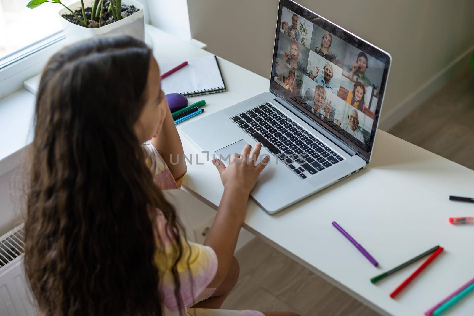 Home schooling. A girl is sitting at a table with a laptop during an online video chat of a school lesson with a teacher and class. Concept of distance education. Self-isolation in quarantine