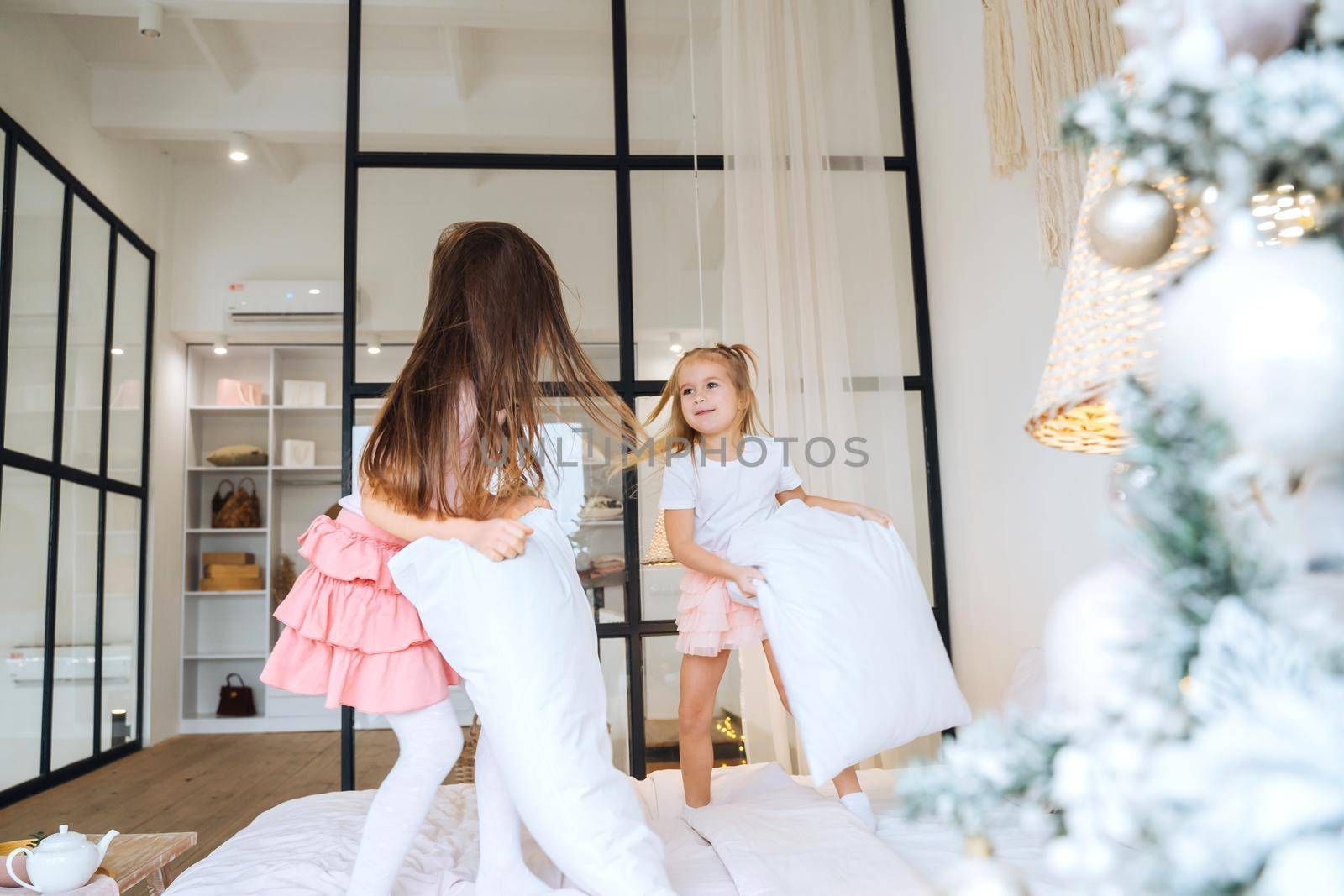 two girls playing with pillows in bedroom