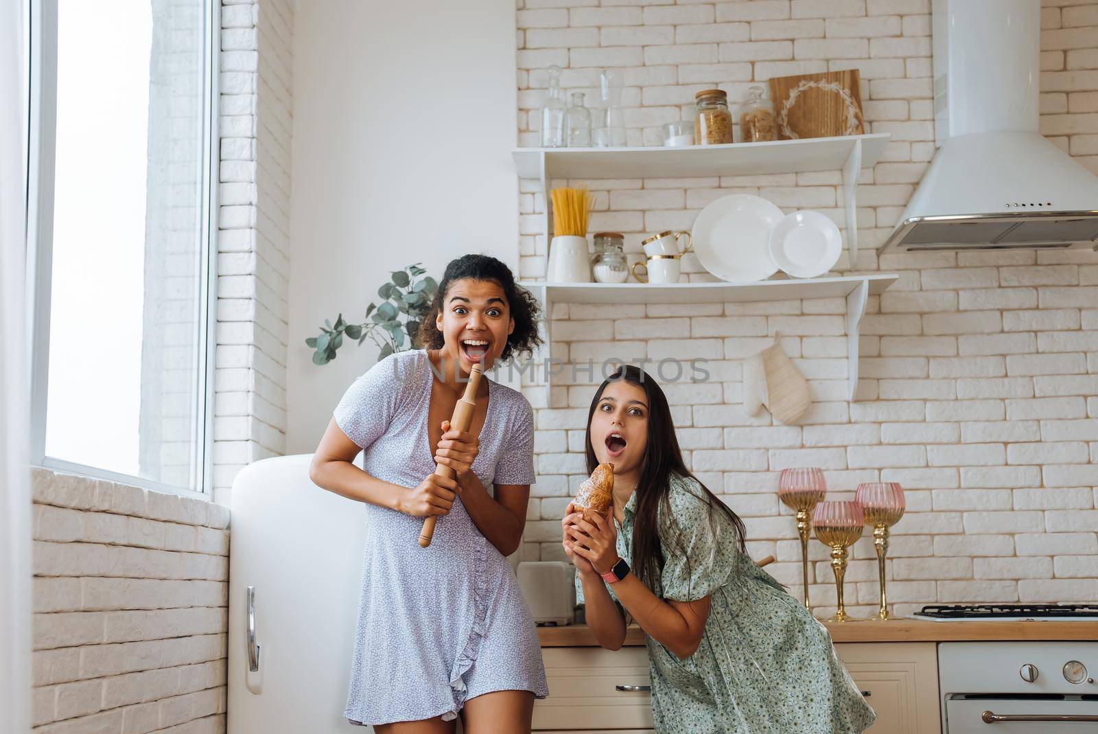 two girls of different races having fun together in the kitchen