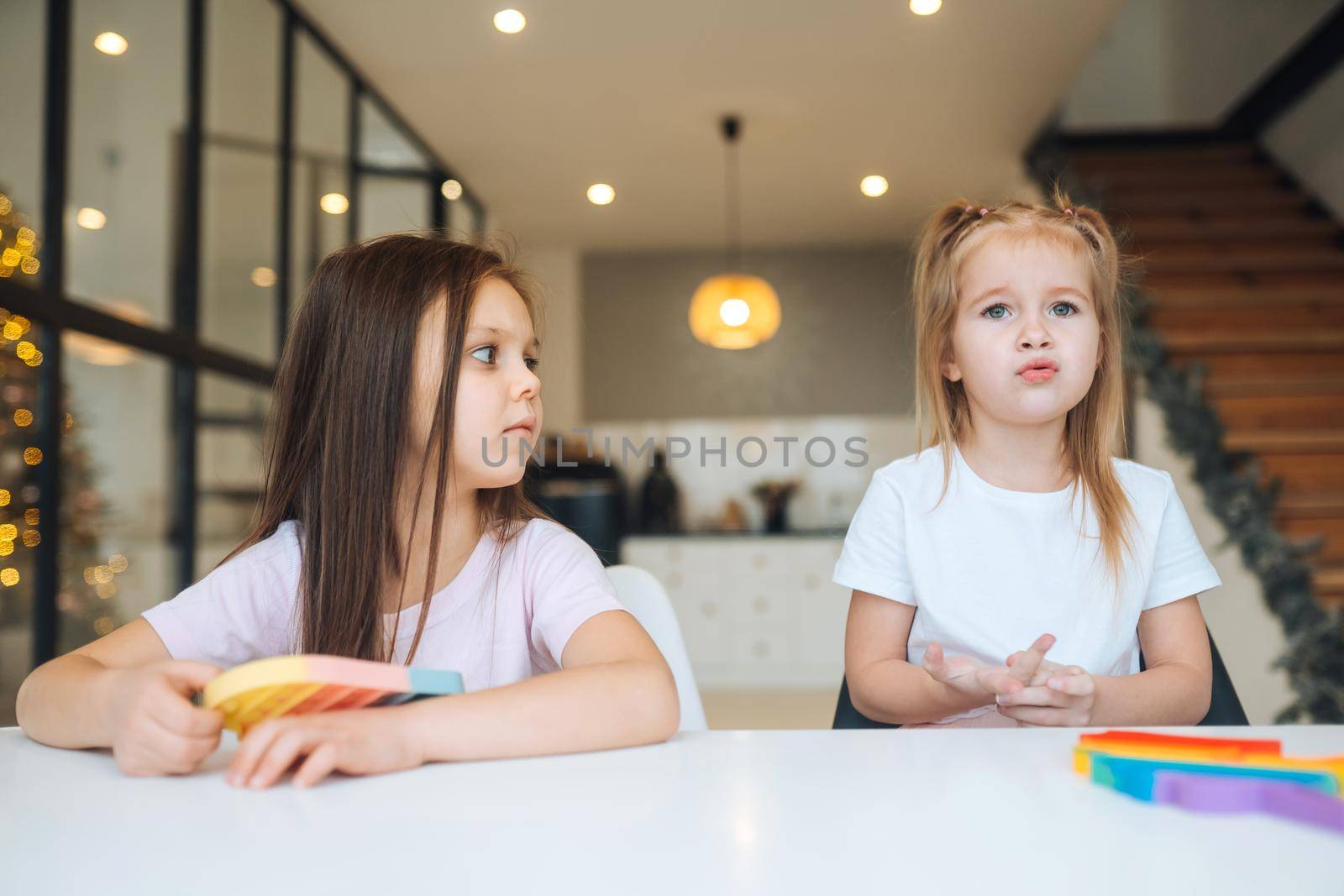 Photo of two little girls playing at the table on the camera indoors