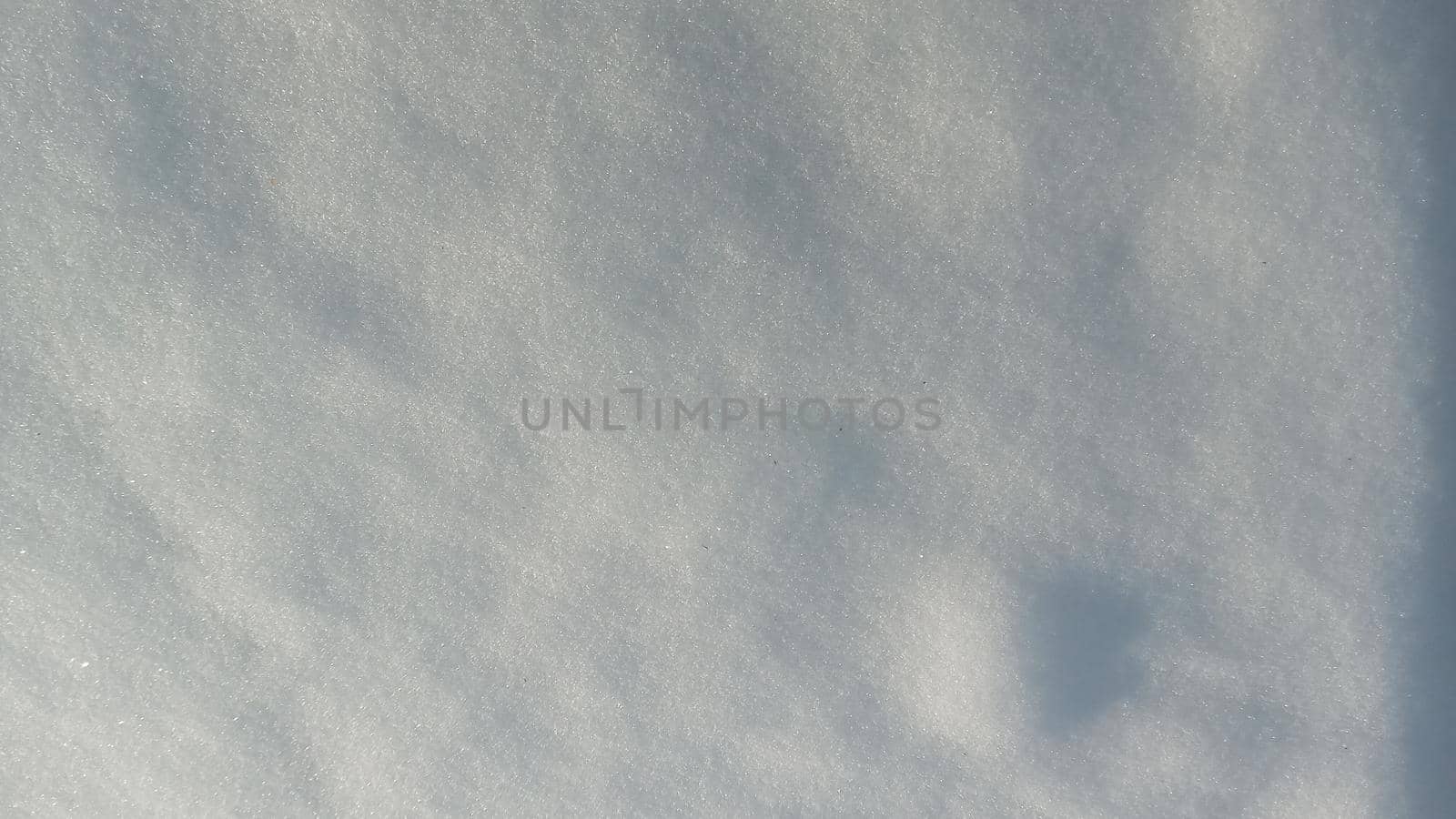 Background with natural snow texture, close-up view from above. Beautiful sunny bright texture of snow in winter season. Selective focus is used.