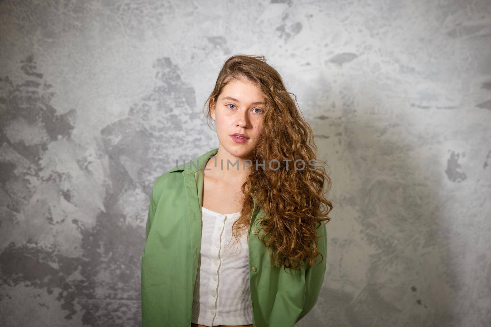 Pretty female looking at camera. Studio shot of good-looking beautiful woman isolated against blank studio wall.