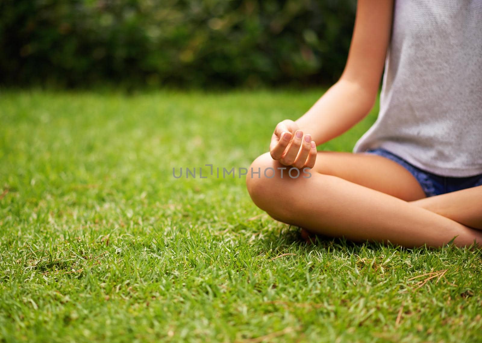 She just loves being outdoors. Cropped shot of a young woman meditating in the garden. by YuriArcurs