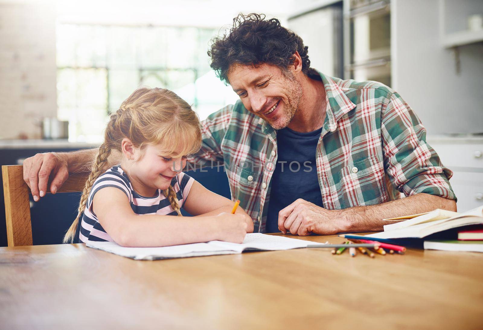 Its important to provide encouragement to kids. Cropped shot of a father helping his daughter with her homework. by YuriArcurs